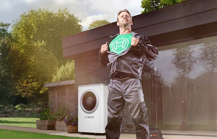 Bosch-installatör som poserar som supermannen med grön t-shirt med tryckt Bosch-logga