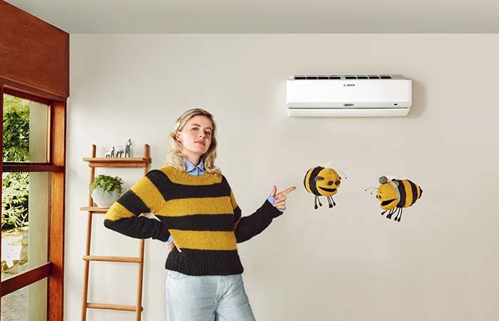 Luft/luftvärmepump Climate 9100i i sällskap av en kvinna och två bin i #LikeABosch-miljö
